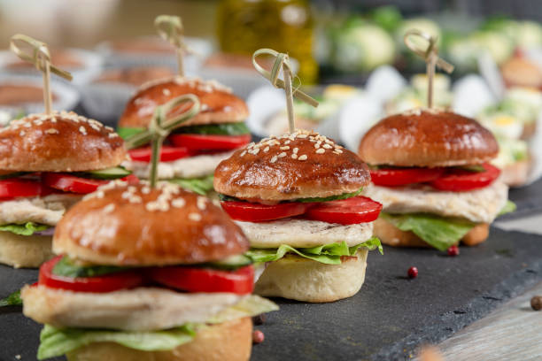 Set of chicken burgers on black board on wooden table stock photo
