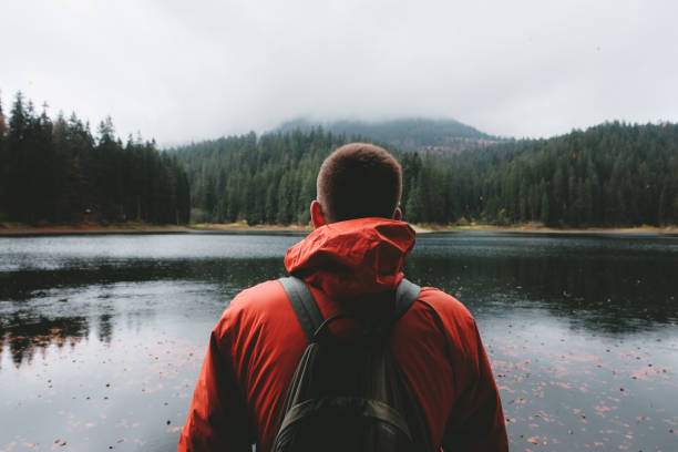 istock Man with backpack looking at beautiful mountain lake 1060036714