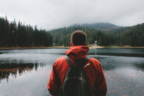 istock Man with backpack looking at beautiful mountain lake 1060036720