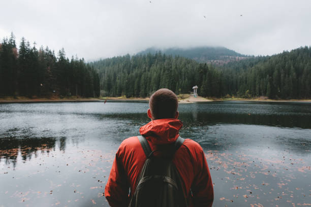 istock Man with backpack looking at beautiful mountain lake 1060036726