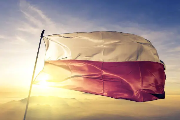 Photo of Poland Polish flag textile cloth fabric waving on the top sunrise mist fog