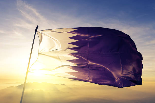 Qatar Qatari flag textile cloth fabric waving on the top sunrise mist fog Qatar Qatari flag on flagpole textile cloth fabric waving on the top sunrise mist fog qatar photos stock pictures, royalty-free photos & images