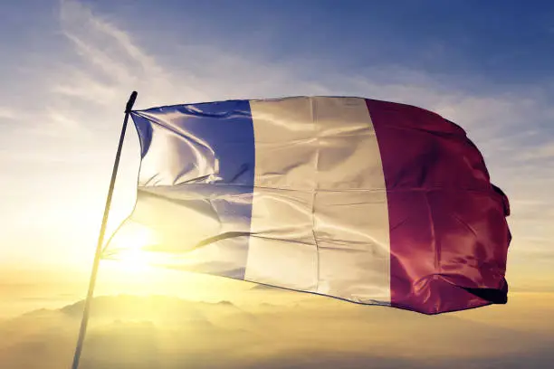 Photo of France French flag textile cloth fabric waving on the top sunrise mist fog