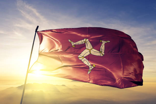 Isle of Mann Manx flag textile cloth fabric waving on the top sunrise mist fog Isle of Mann Manx flag on flagpole textile cloth fabric waving on the top sunrise mist fog mann stock pictures, royalty-free photos & images