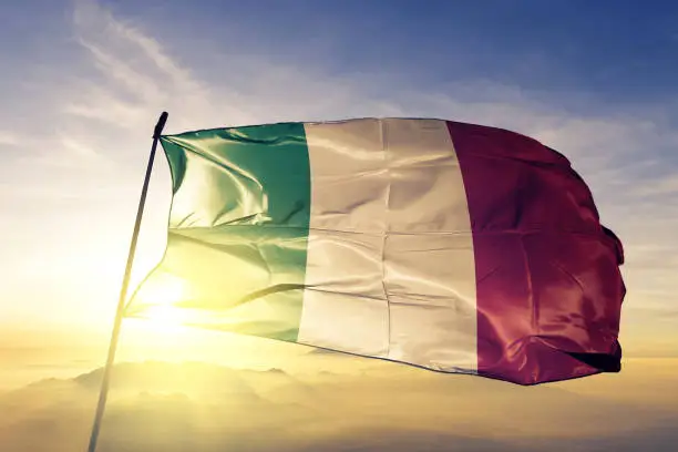 Photo of Italy Italian flag textile cloth fabric waving on the top sunrise mist fog