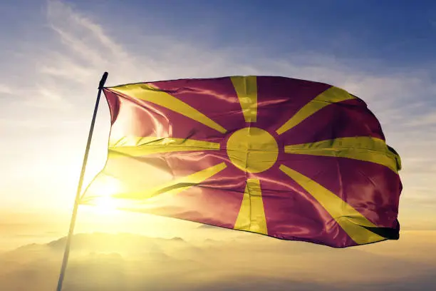 Macedonia Macedonian flag on flagpole textile cloth fabric waving on the top sunrise mist fog