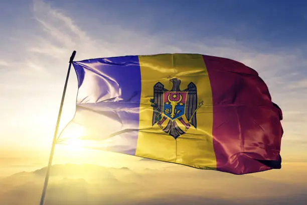 Moldova Moldovan flag on flagpole textile cloth fabric waving on the top sunrise mist fog