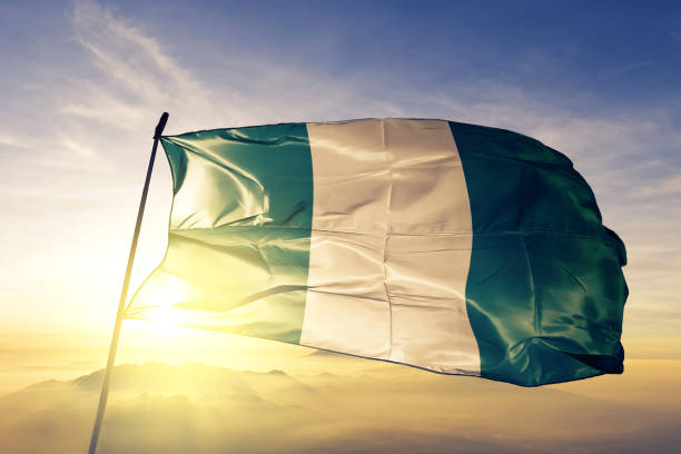 nigeria nigeria flagge textil tuchgewebe winken auf der oberen sonnenaufgang nebel nebel - nigeria stock-fotos und bilder