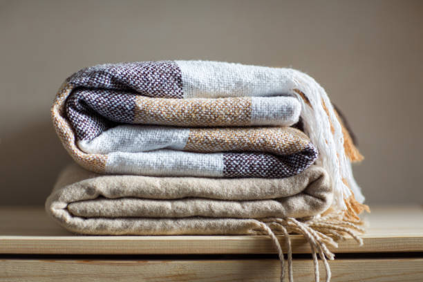 istock home textile. stack of beige wool blankets on a wooden shelf. 1060041340