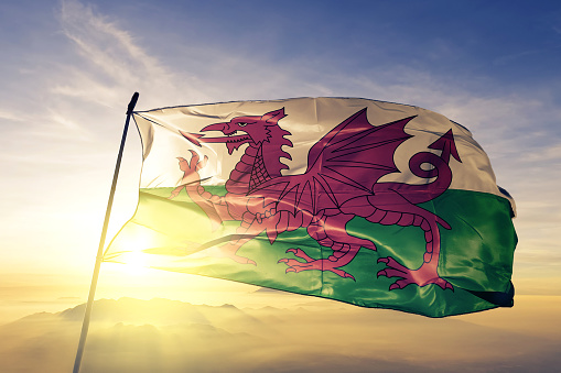 Wales Welsh United Kingdom Great Britain flag textile cloth fabric waving on the top sunrise mist fog