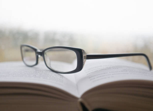 istock Eyeglasses on an open book with window on background in rainy weather 1060072198