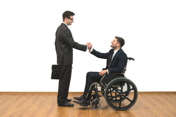 o homem e a deficiente no handshake de cadeira de rodas sobre o fundo de parede branca - isolated smiling business person handshake - fotografias e filmes do acervo