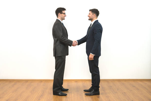 o handshake de dois empresários no fundo parede branca - isolated smiling business person handshake - fotografias e filmes do acervo