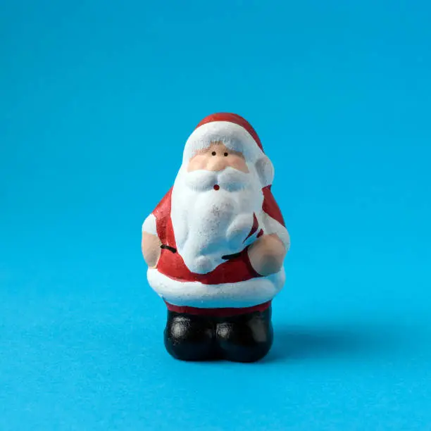 Photo of Miniature Santa Claus on blue background. Christmas New Year min