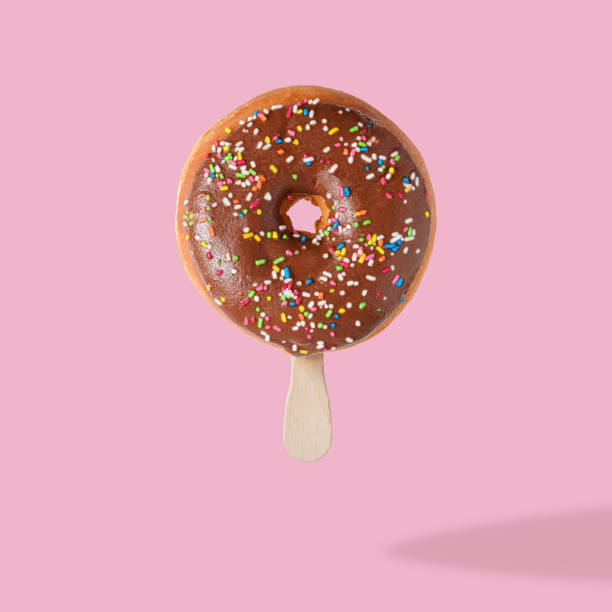 istock Glazed donut with ice cream stick on pink pastel background. Fla 1060094026