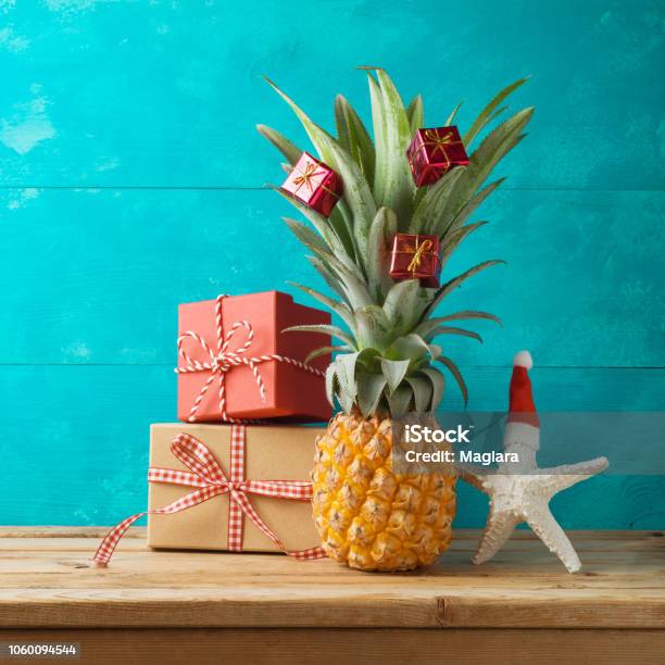 Christmas Holiday Concept With Pineapple As Alternative Christmas Tree And Gift Boxes On Wooden Table With Copy Space Stock Photo - Download Image Now