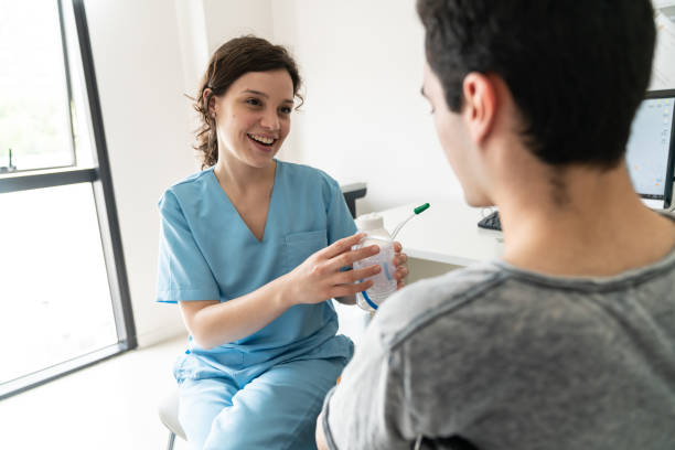friendly therapist talking to unrecognizable male patient of a breathing exercise with the spirometer - nurse doctor scrubs male imagens e fotografias de stock