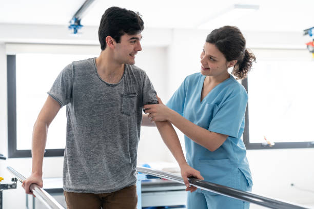 istock Male patient and therapist looking at each other while he is leaning on parallel bars to walk 1060112800