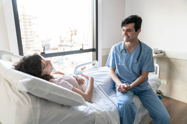 istock Friendly nurse checking up female hospitalized patient sitting next to her talking 1060112806
