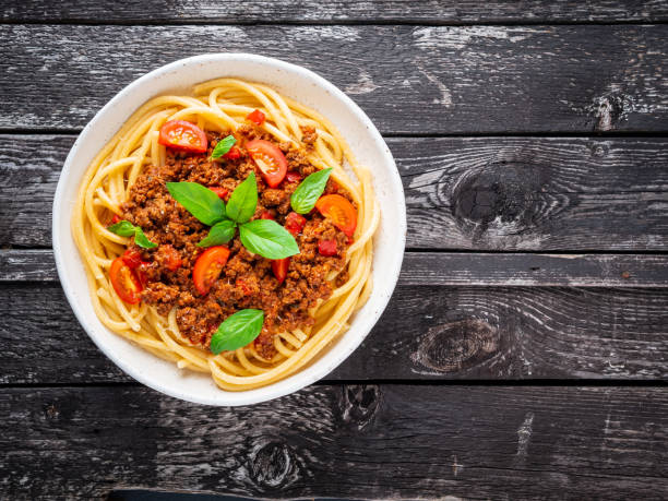 istock pasta bolognese with tomato sauce, ground minced beef, basil leaves on dark rustic wooden table, top view, copy space 1060120404