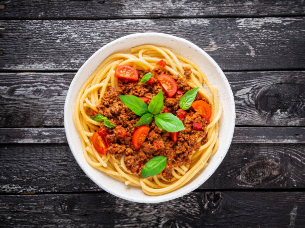 istock pasta bolognese with tomato sauce, ground minced beef, basil leaves on dark rustic wooden table, top view 1060120440