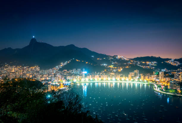 veduta aerea di rio de janeiro e guanabara bay con il monte corcovado di notte - rio de janeiro, brasile - rio de janeiro night sugarloaf mountain corcovado foto e immagini stock