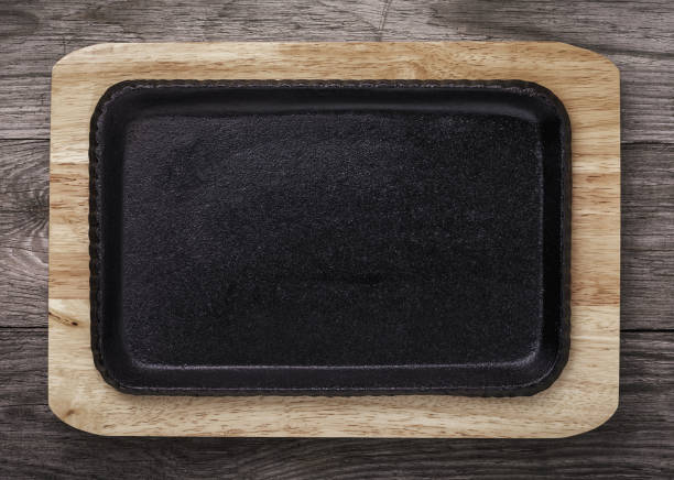 Empty pig-iron baking sheet on a wooden support. Food background stock photo