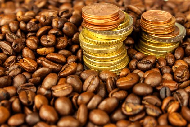 coffee beans and money. fair trade. sale of coffee. commodity trade. fresh coffee beans. column of euro coins. - food currency breakfast business imagens e fotografias de stock