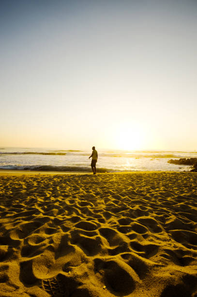 istock Silhouette Of A Young Man Walking On A Colourful Beachside 1060130268