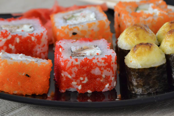 istock Sushi and rolls on a black plate with chopsticks. 1060139714