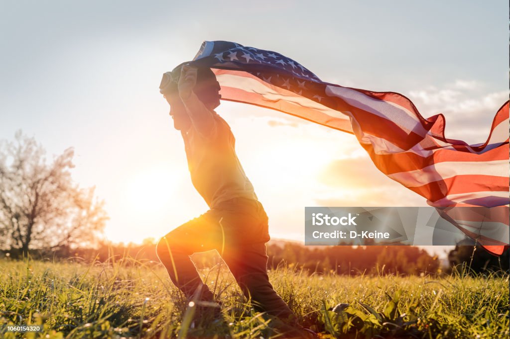 Independence day Little boy running with American flag at sunset Fourth of July Stock Photo