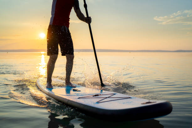 istock man paddleboarding on lake at sunset 1060156604