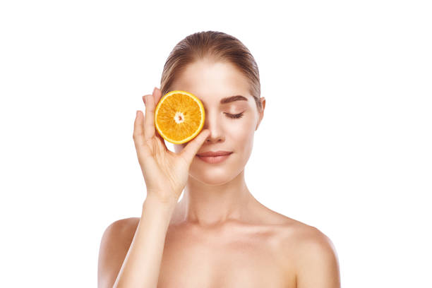 istock Beautiful womans face with orange close-up studio on white. 1060178756