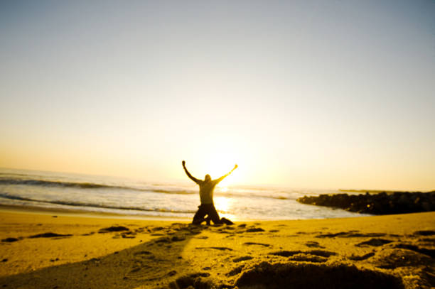 istock Arms Outstretched: Silhouette Of A Young Man On A Colourful Beachside 1060184106