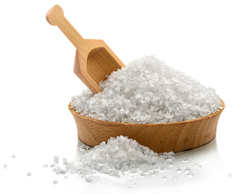 Bowl of coarse salt with a serving scoop. \nIsolated on white.