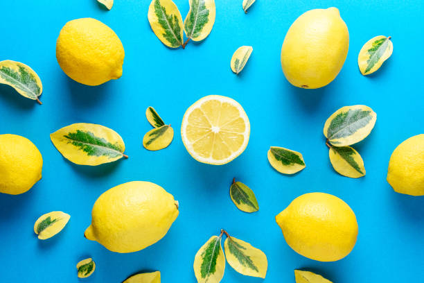 istock Creative summer pattern made of lemons and green leaves on blue 1060193606