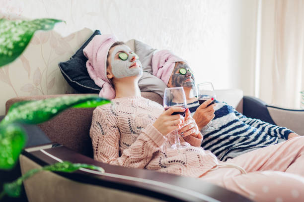 mother and her adult daughter applied facial masks and cucumbers on eyes. women chilling while having wine - mother enjoyment built structure human head imagens e fotografias de stock