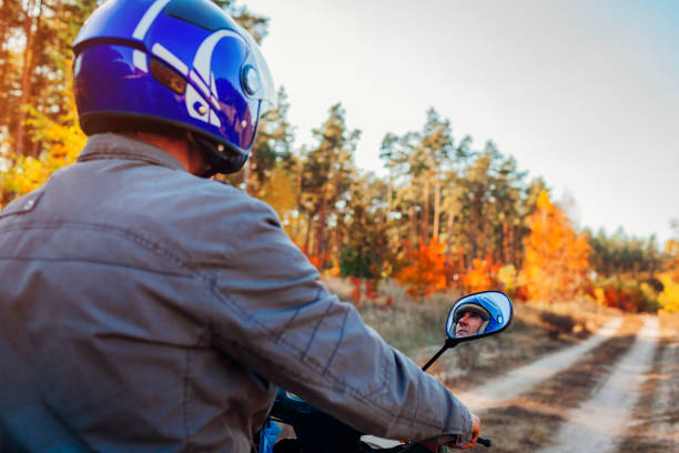 istock Senior man riding scooter on autumn forest road. Driver in helmet riding moped 1060200026
