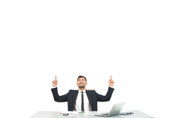 The businessman sitting at the desktop and gesturing on the white background
