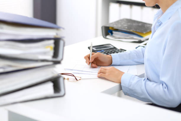 istock Unknown female bookkeeper or financial inspector calculating or checking balance, making report, close-up. Internal Revenue Service at work with financial document. Tax and audit concept 1060201790