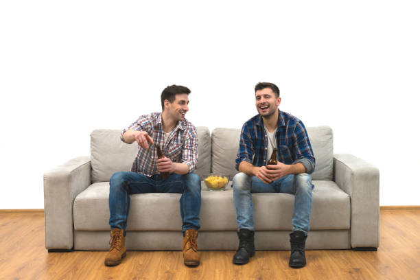 istock The two men drink a beer with chips on the sofa on a white wall background 1060203862