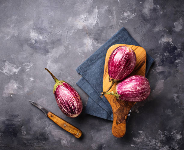 istock Fresh striped purple aubergines on grey background 1060210424