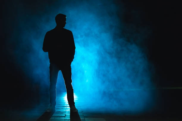 der mann im blauen nebel steht. abend nacht - raum eine person dunkelheit stehen gegenlicht stock-fotos und bilder