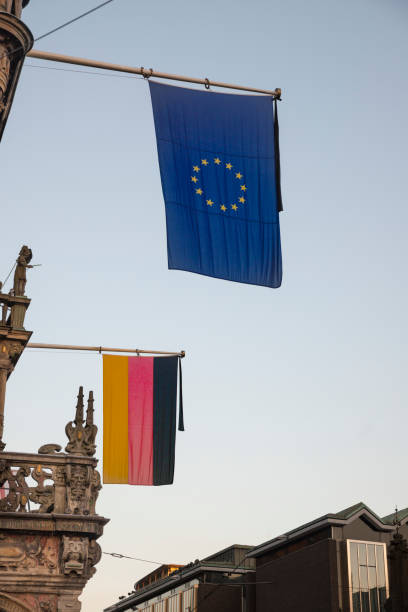 European Union EU flag alongside with German flag hanging from pole in Bremen, Germany. Old 1500s building.