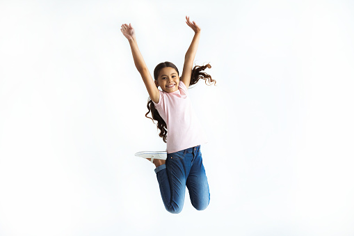 The happy girl jumping on the white wall background