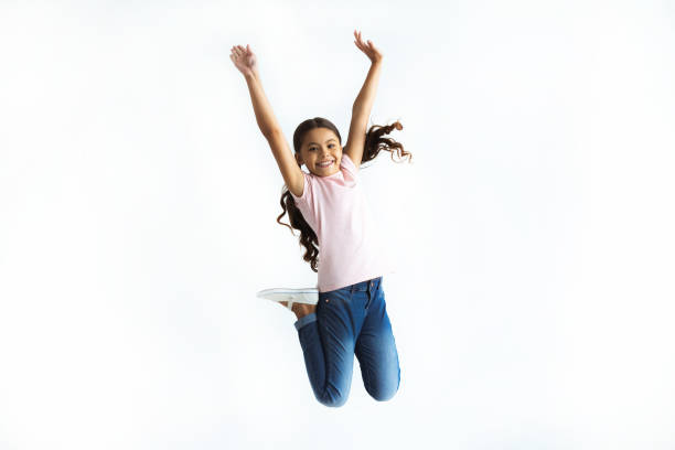 The happy girl jumping on the white wall background stock photo