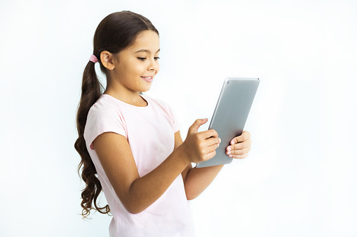 The happy girl holding the tablet on the white wall background