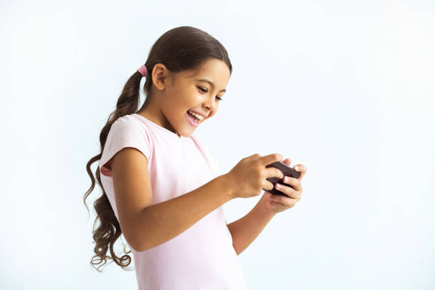 The happy girl holding a phone on the white wall background stock photo