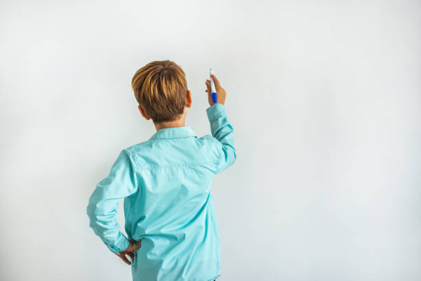 il ragazzo che scrive sulla parete bianca - little boys measuring expressing positivity intelligence foto e immagini stock