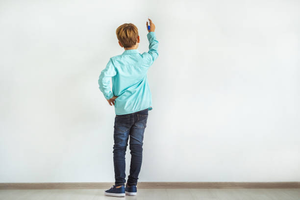 il bambino che scrive sulla parete bianca - little boys measuring expressing positivity intelligence foto e immagini stock